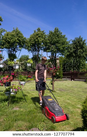 Boy mowing the garden with an electric lawn mower