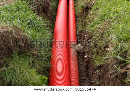 A pair of red cable pipes in a trench