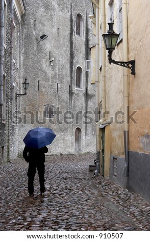 Old city street and man with blue umbrella