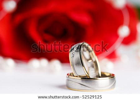 stock photo two wedding rings with a pearl necklace and a red rose in the
