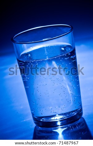 blue glass filled with soda water on white ground