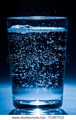 blue glass filled with soda water on white ground