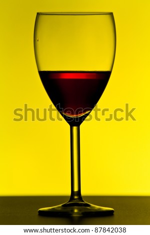 wine glass with red wine on yellow background with strong contrast