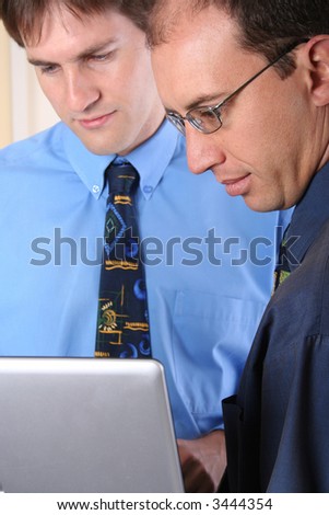 Two businessmen with laptop. Rear model outside DOF.