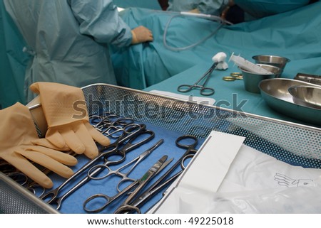 Surgical tools, with surgeons busy performing operation in background. Short DOF