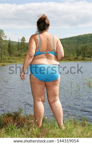 Obese woman by a tarn going into the water