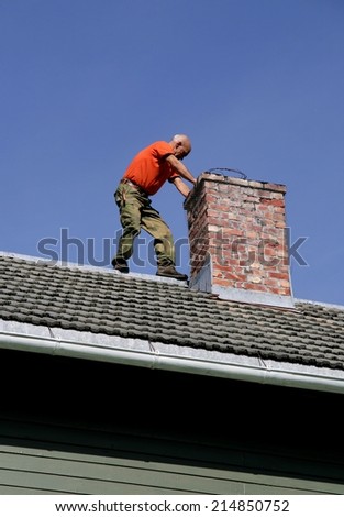 Man on the roof of his house inspecting his chimney