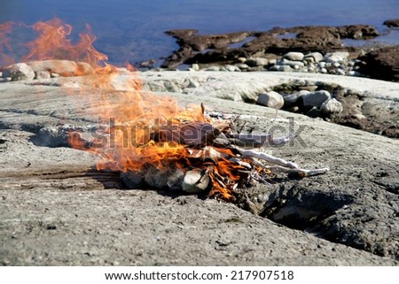 Bonfire on the rocks by a lake
