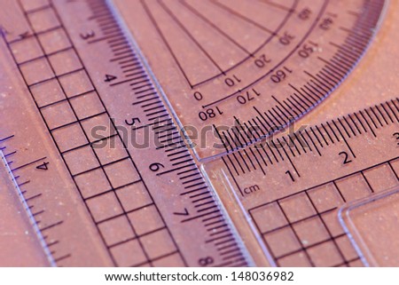 Close up of a protractor, set square and ruler with blue edges on tile background. Shallow depth of field