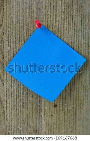 Blue note on a wooden background with red thumb-tack