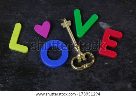Antique key on a slate background with the word love in letters