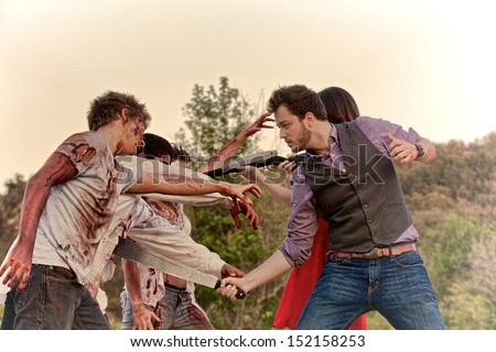A man and woman fight off three attacking zombies