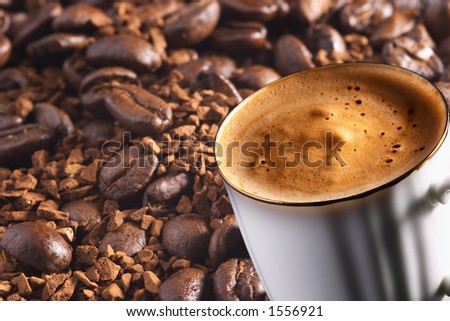 Cup of coffee over coffee-beans and instant coffee background, focus on front rim of cup