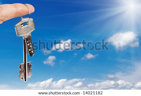 Finger with key against blue sky background