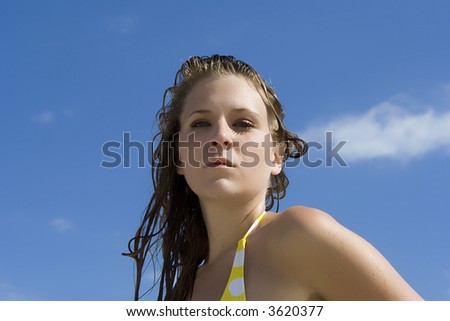 Woman with wet hair looking into camera.  Blue sky in the background