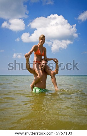 Man and woman having good time on a beach, man carrying woman on his shoulders