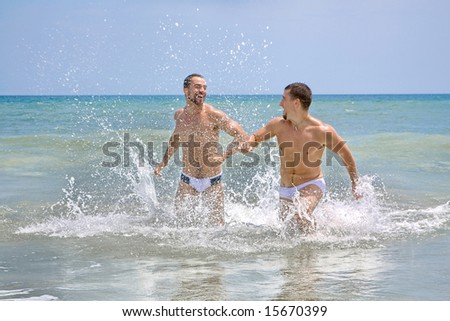 Two men at the beach, running in the water