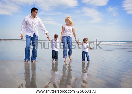 Family walking on a beach, all wearing jeans and white shirts
