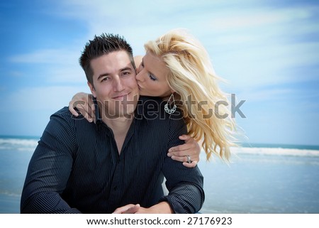 Man and a woman at the beach. Woman kissing man.