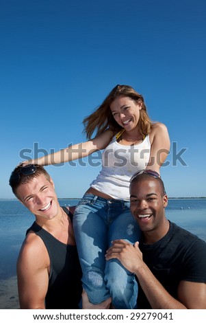 Two man and one woman at the beach having fun