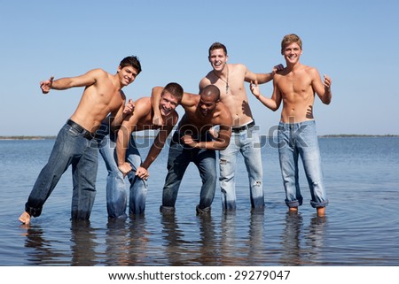 5 men in jeans at the beach, standing in the water