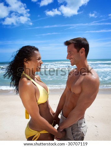 Fun couple standing at the beach in swim suits