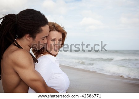 Black man and white woman standing at the beach