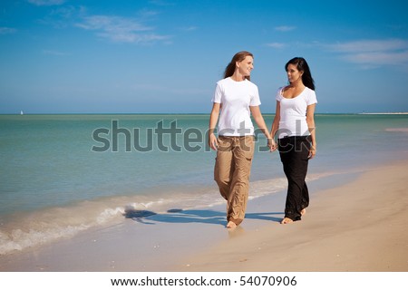 stock photo Lesbian couple walking on beach holding hands