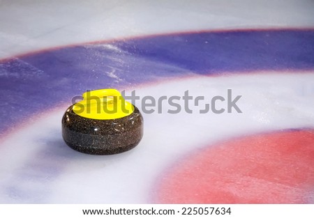 A single curling stone on the ice of a curling rink