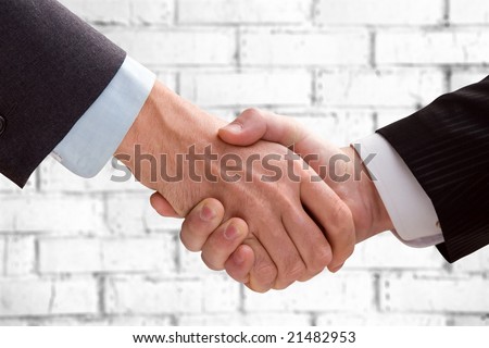 Two business men shaking hands on a background of a brick wall