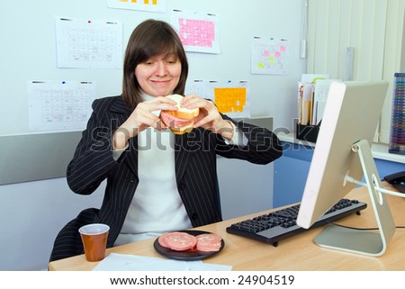 The young woman has breakfast a sandwich with sausage on work