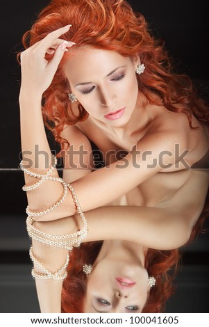 closeup portrait beautiful redhead young woman with mirror and pearl necklace on her hand