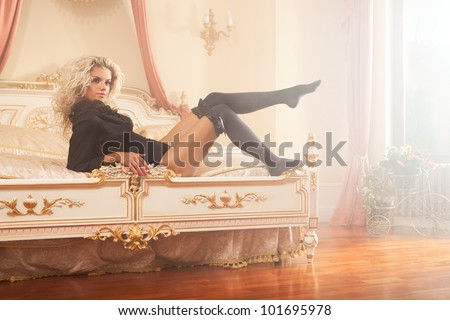 glamour picture of pretty girl in black lingerie laying on the bed in luxury interior