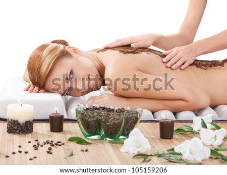 portrait of happy beautiful young woman getting back massage with coffee scrub at spa