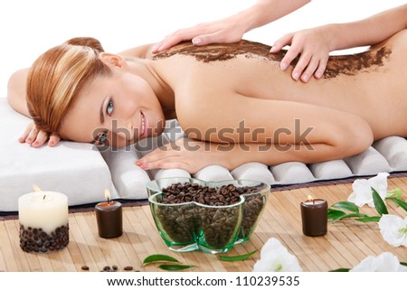 portrait of happy beautiful young woman getting back massage with coffee scrub at spa
