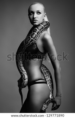 black and white picture of sexy young woman in bikini posing with python