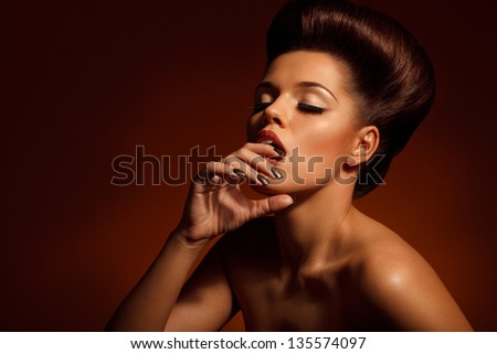creative portrait of beautiful young woman with closed eyes biting her finger against brown background