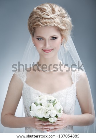 portrait of happy young woman in white wedding dress and bridal veil with flowers