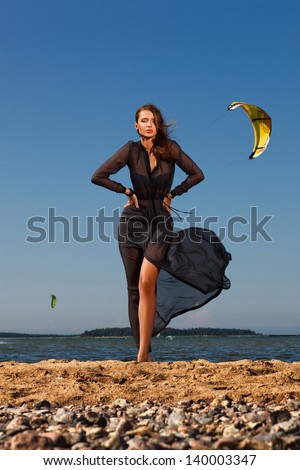 picture of beautiful young woman in blowing dress posing on the beach
