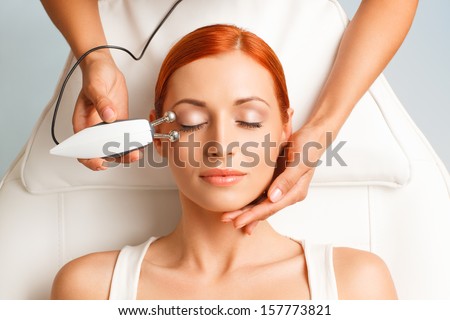 closeup portrait of lovely redheaded woman with closed eyes and hand with medical lifting device touching her face