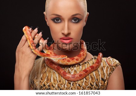 closeup portrait of sexy young woman holding orange snake against black background