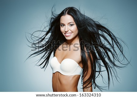 portrait of happy girl with long dark blowing hair against blue background