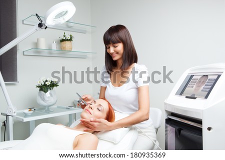 picture of nice beautician doing oxygen therapy for young woman laying down with closed eyes in a beauty salon