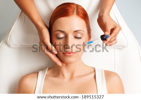 closeup portrait of lovely redheaded woman with closed eyes and hand with medicine dropper