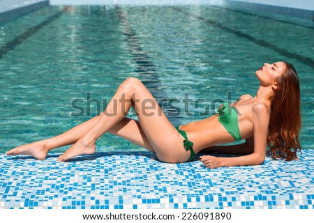 picture of beautiful woman in bikini lying on side of the pool