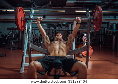 weight lifter lifting a barbell on an incline bench at gym