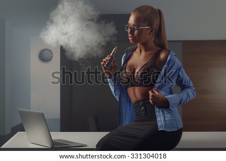 sexy secretary sitting on the table with e-cigarette and vaping in office