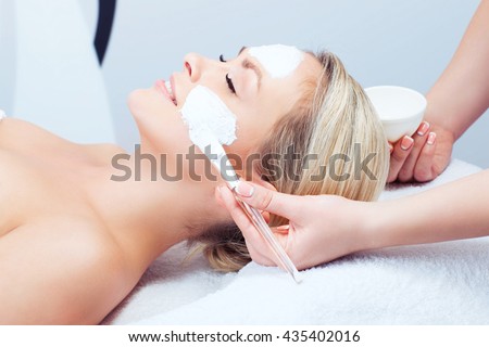 Hardware cosmetology. Closeup picture of lovely young woman with cream mask in a beauty parlour.