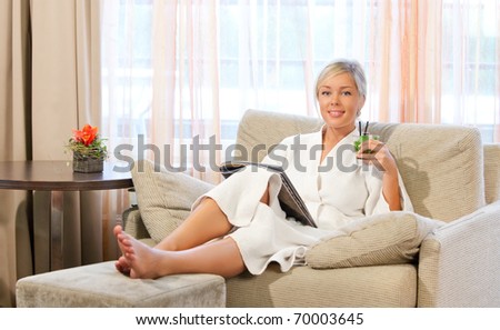 relaxed girl reading a magazine on a chair while having mojito cocktail