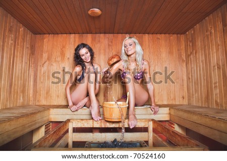 two happy young women relaxing in a dry sauna